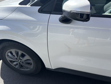 NZ rental car insurance — close-up of door panel scratch on rental Kia Carnival, South Island New Zealand