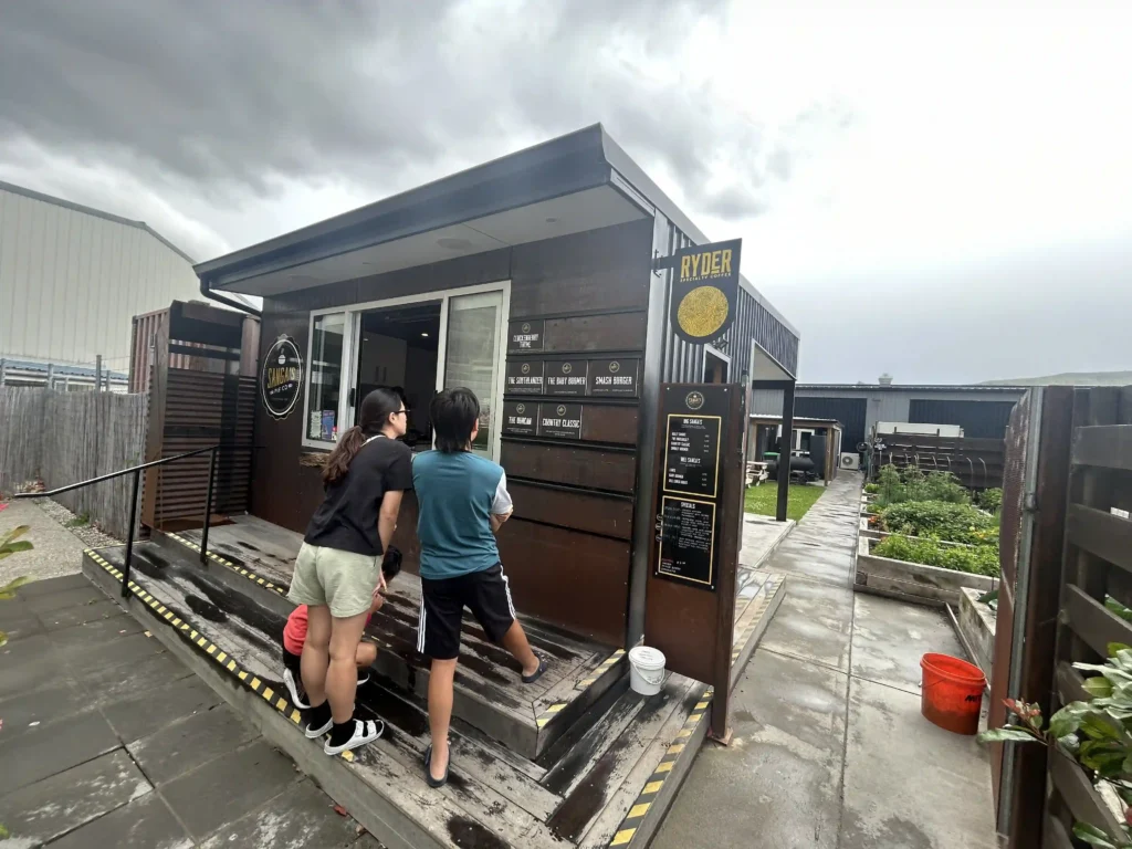 anga's Pie Co exterior in Cromwell South Island — dark shipping container shopfront in industrial area with Ryder Specialty Coffee sign, overcast sky
