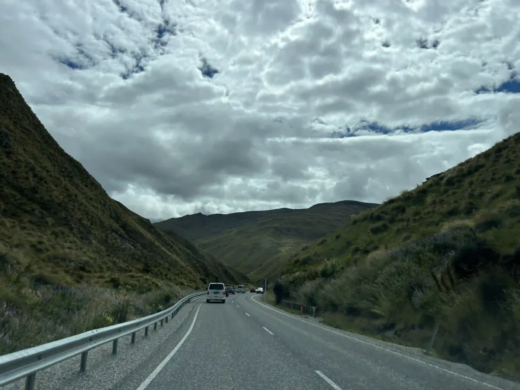 NZ rental car insurance risk — narrow single-lane South Island mountain road with no verge