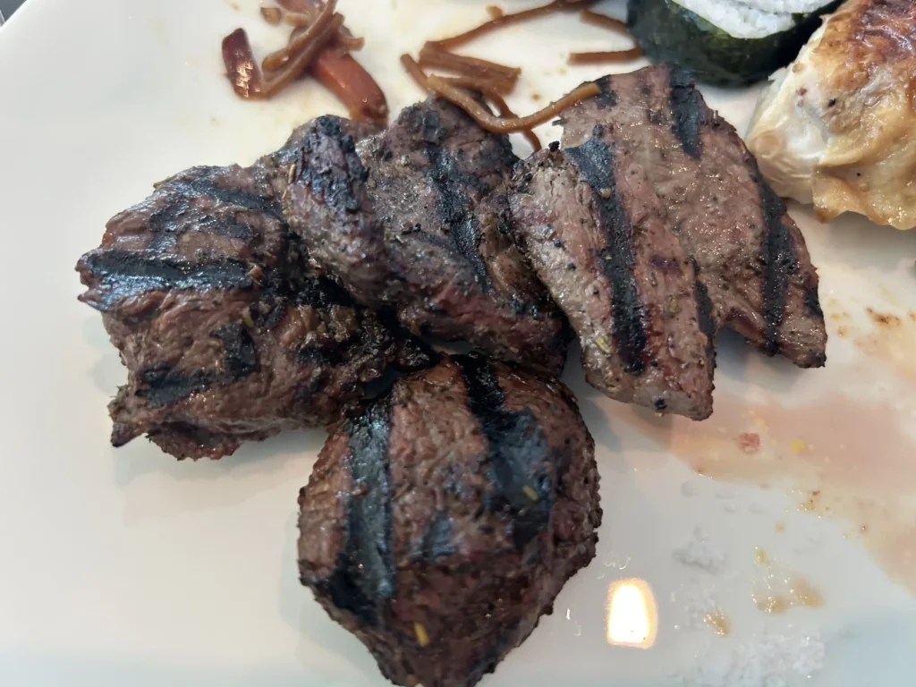 Grilled venison steak at Stratosfare buffet restaurant, Queenstown Skyline — New Zealand farmed deer, char-grilled and served at the mountaintop buffet